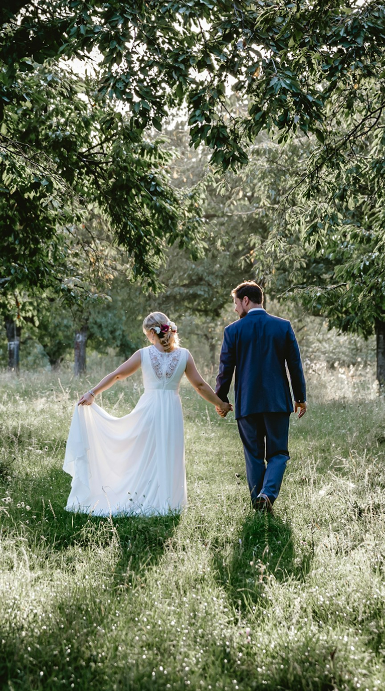 Bride and groom walking through a sunlit garden