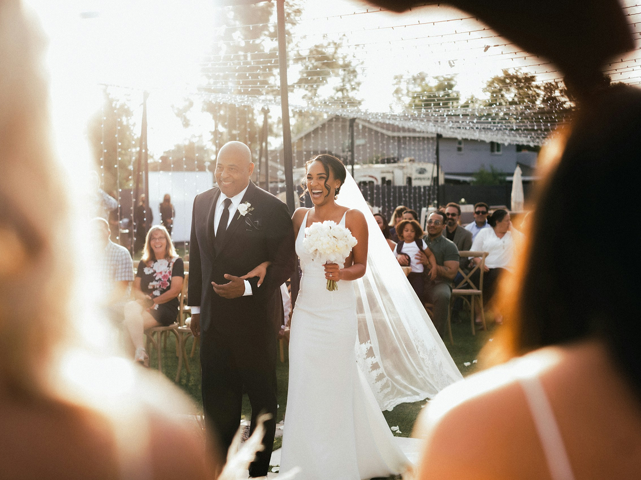 Bride escorted through guests at an outdoor wedding ceremony